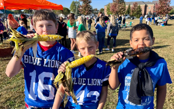 Three Belle Aire Intermediate students eat fresh ears of corn at Blue Lion Agriculture Day